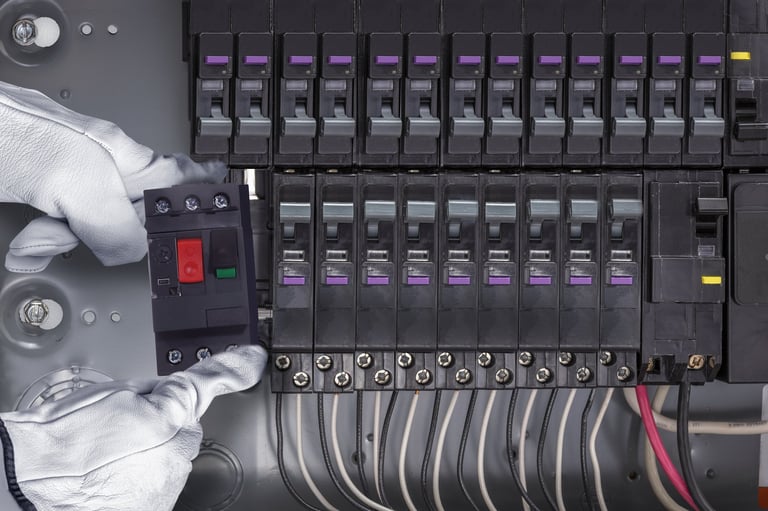 Close-up of a professional electrician wearing safety gloves installing a circuit breaker inside an electrical distribution panel.